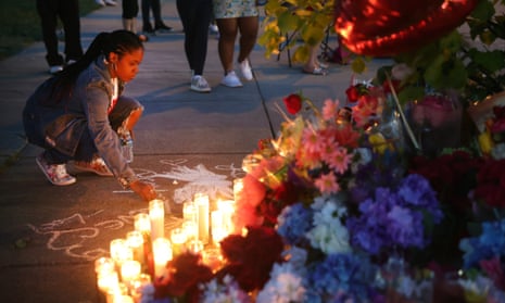 A woman chalks a message at a makeshift memorial outside of Tops market in Buffalo, New York.