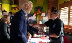 Biden shakes an elderly veteran's hand as people gather around in a Mexican restaurant,