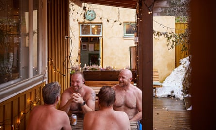 A group of bare-chested men sit outside at a picnic table with beers, at Ranjaportti