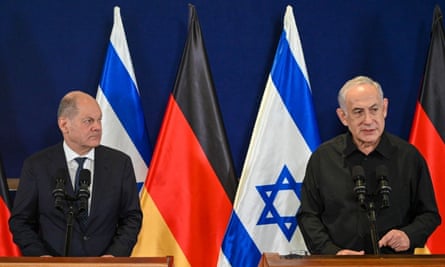 Olaf Scholz and Benjamin Netanyahu stand in front of their countries’ flags at a press conference