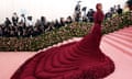 Cardi B in a spectacular red dress with a long, wide, ruffled train making her way up the steps to the gala.