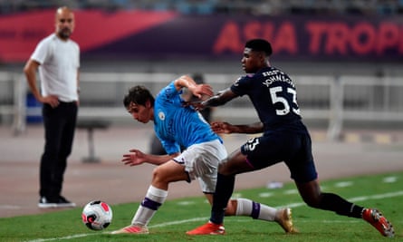 Manchester City’s Adrián Bernabé battles for the ball as Pep Guardiola watches on.