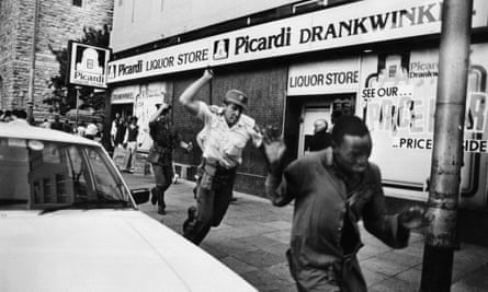 A South African police officer chasing a demonstrator with a sjambok whip