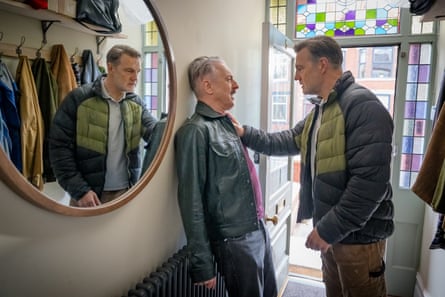 A man in a home's hallway pushing another man against a wall