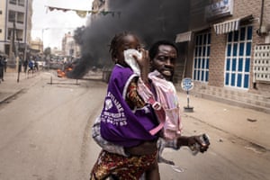 Dakar, Senegal. A man runs with his daughter as she covers her nose from teargas