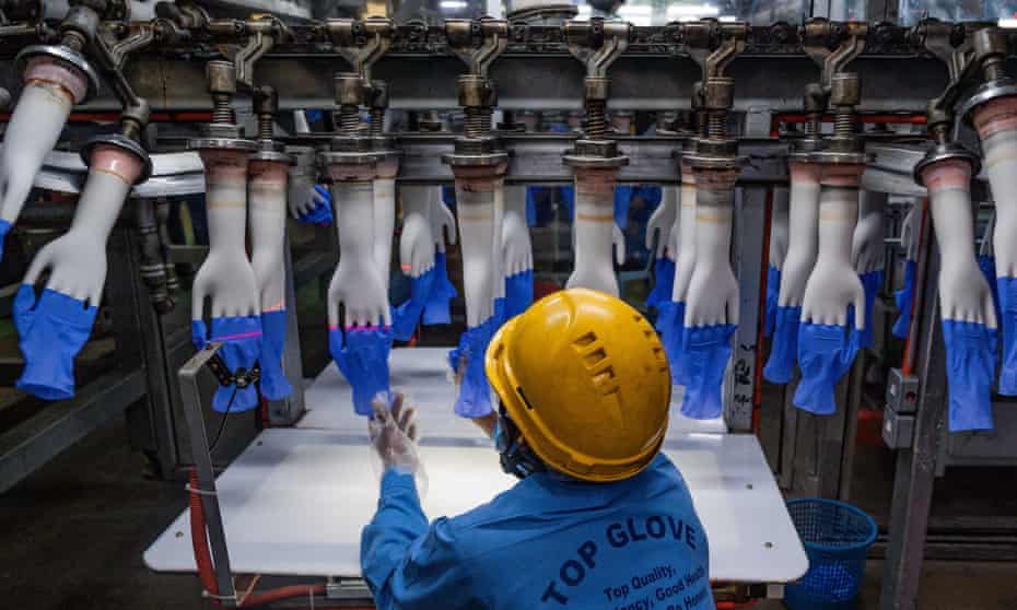 A worker inspects disposable gloves in August at the Top Glove factory production line on the outskirts of Kuala Lumpur, Malaysia.