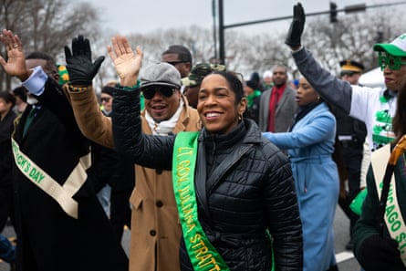 People wave while walking in a parade.