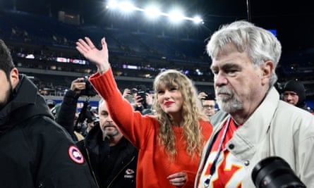 taylor swift wearing a red sweater in a stadium surrounded by people