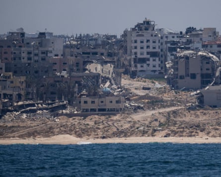 Destroyed buildings in Palestine, with a beach and the ocean in the foreground