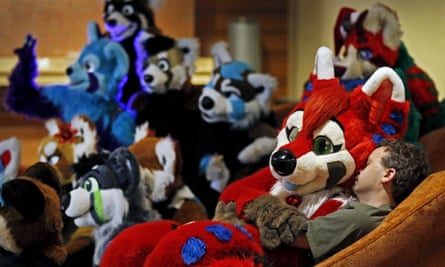 an attendee dressed in a fursuit costume sits in the lap of a man at the Midwest FurFest.