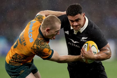 New Zealand’s Codie Taylor is tackled by Max Jorgenson as rain falls