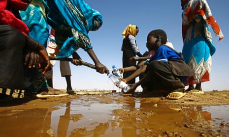 A Sudanese woman fills water bottles held by a young boy about 60km north of El-Fasher, the capital of the North Darfur state, on 9 February 2017. 