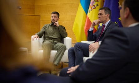Volodymyr Zelenskiy sat on a white chair with people in the foreground
