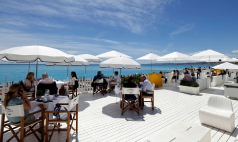 Customers enjoy lunch on the terrace of a beach restaurant in Nice