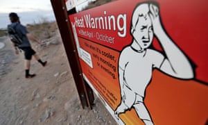 A hiker in Phoenix walks past a heat warning sign at sunrise in July. Arizona’s largest city is also and ‘urban heat island’ – a phenomenon that pushes up temperatures in areas covered in heat-retaining asphalt and concrete.