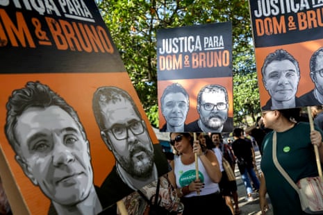 People hold signs with the portraits of two men with the words 'Justica para Dom & Bruno'