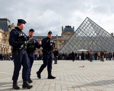 Three armed police outside the Louvre pyramid