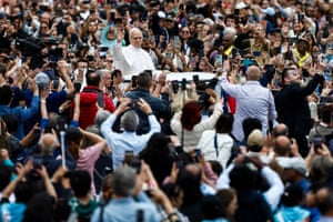 Pope Leo XIV looks out over waving crowds as he is transported in an open-top popemobile