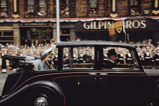 Queen and Prince in back of a black car in front of huge cheering crowd