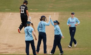 New Zealand’s Suzie Bates walks as England’s Tammy Beaumont celebrates with teammates after taking a catch to dismiss her.