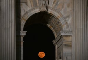 The full moon rises behind the Arco della Pace, Milan, Italy.