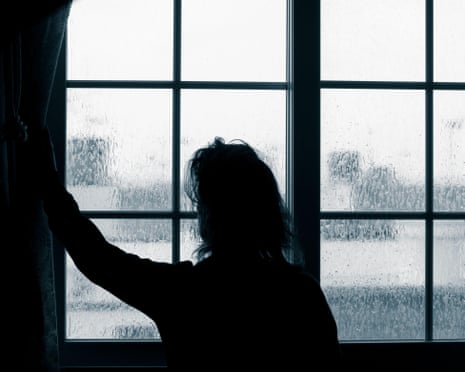 A woman looks out a window on a rainy day