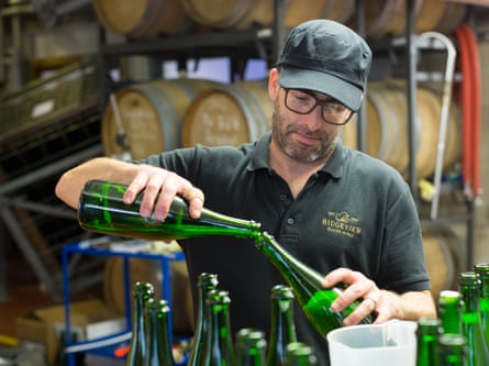 An employee tops up bottles of white sparkling wine during the bottling process at the Ridgeview Estate Winery.