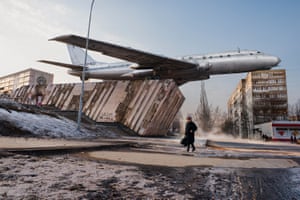 Man in street walking beneath airplane, Rybinsk, Russia, 2015