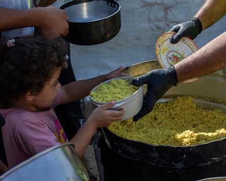 Young girl receiving a portion of cooked rice