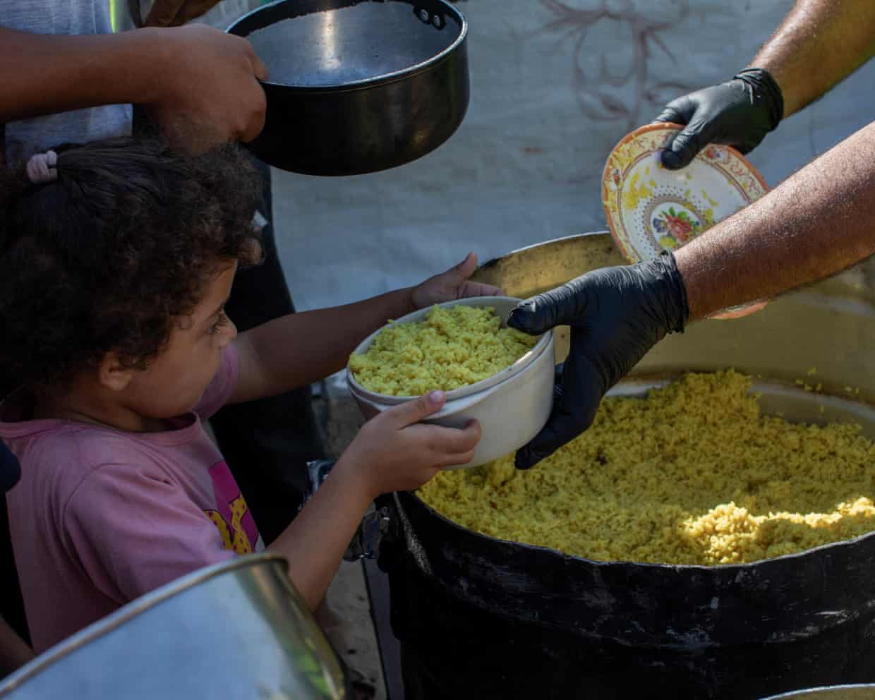 Young girl receiving a portion of cooked rice