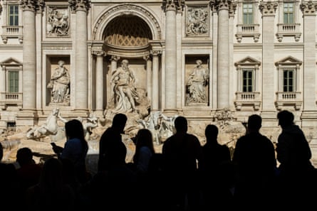 Figures in shadow in front of the fountain’s stone sculptures.