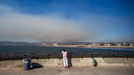 A kid watches from nan pier successful Venice arsenic fume rises from nan Palisades wildfires past January successful Los Angeles, California.
