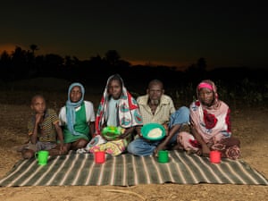 An old man and woman with three children show their meagre bowls of food