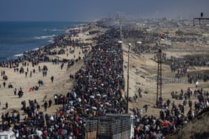 Hundreds of Palestinians move along a road by the sea