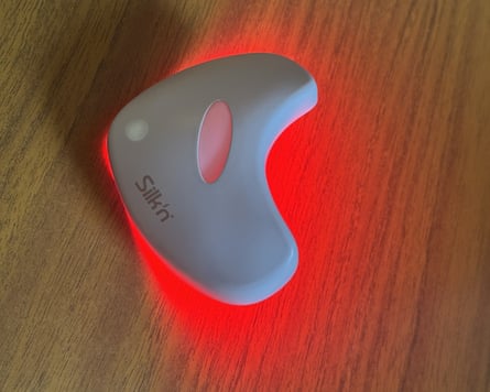 Silk n Lumilips LED mask which is white and oversized lip shaped. It glows red underneath on to the table.