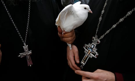 A Greek Orthodox priest holds a dove before a ceremony on banks of the Jordan River in the West Bank.