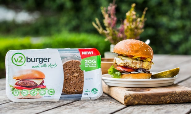 A packet of v2foods burgers and a cooked burger on a plate