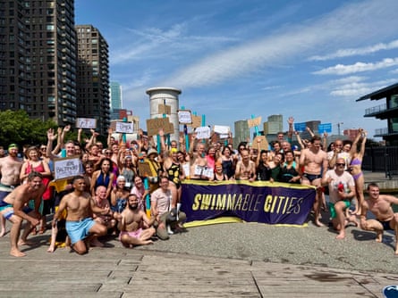 Swimmers stand around a banner which reads ‘swimmable cities’