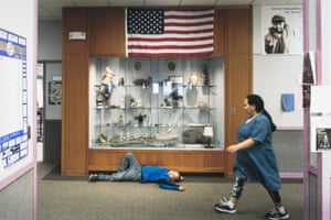 Boy lying on the floor in front of a museum display, under American flag.