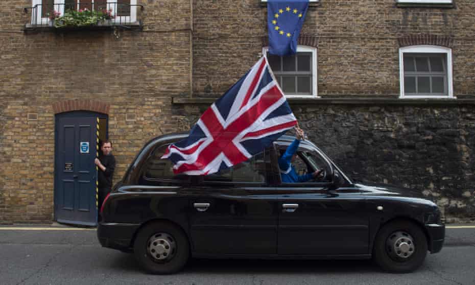 A London Black taxi driver flies a British flag as he drives through a street in central London