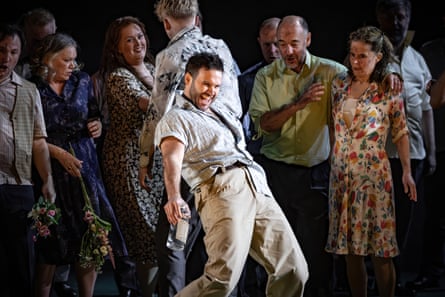A man dances merrily with a crowd of people behind him.