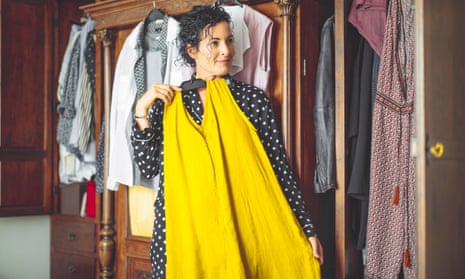 Woman checks a yellow outfit from her wardrobe in front of an unseen mirror