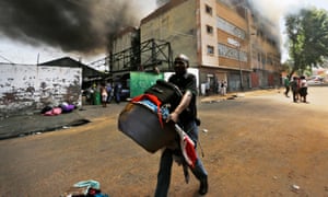 A recently evicted man runs away carrying his belongings as a warehouse burns in central Johannesburg