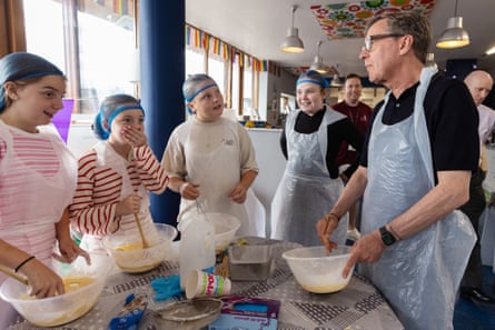 Alan Milburn with local children at a youth centre. Everyone has aprons and food mixing bowls