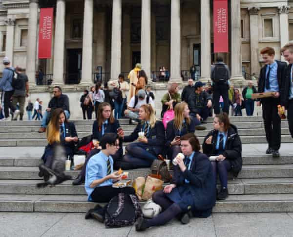 A group of British school students eat lunch on the steps of the National Gallery in London, England