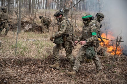 Soliders in camouflage in a forest with burning grass