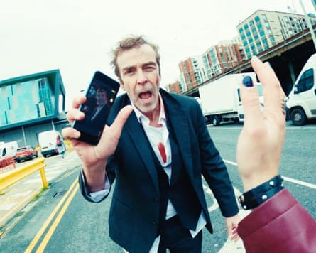 Hannah in middle of the road holding up a phone and looking irate