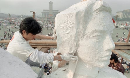 A student plasters the neck of the ‘Goddess of Democracy’, a replica of the Statue of Liberty, on 30 May 1989 in Tiananmen Square.