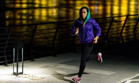 A woman jogging by a river at night.