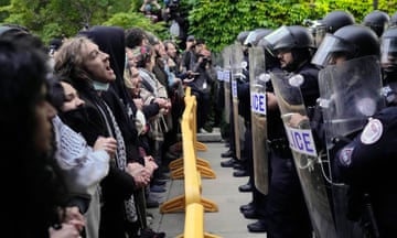 Students and armored police line up in front of each other.